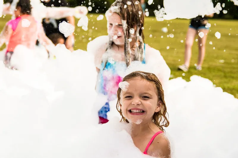 Young girl smiling while covered in foam at a foam party event