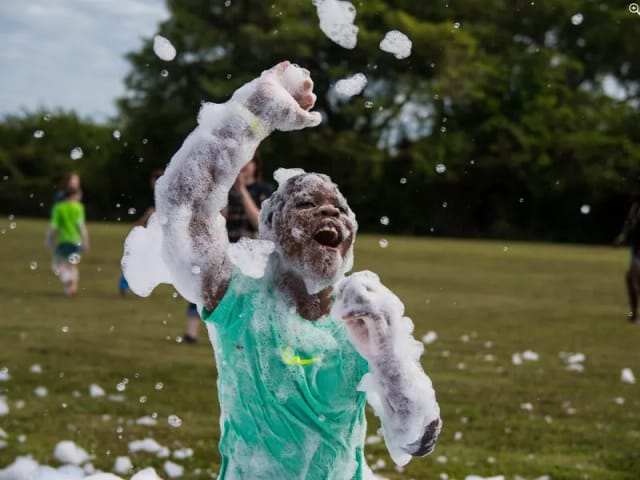 Kid playing in foam on a sunny field