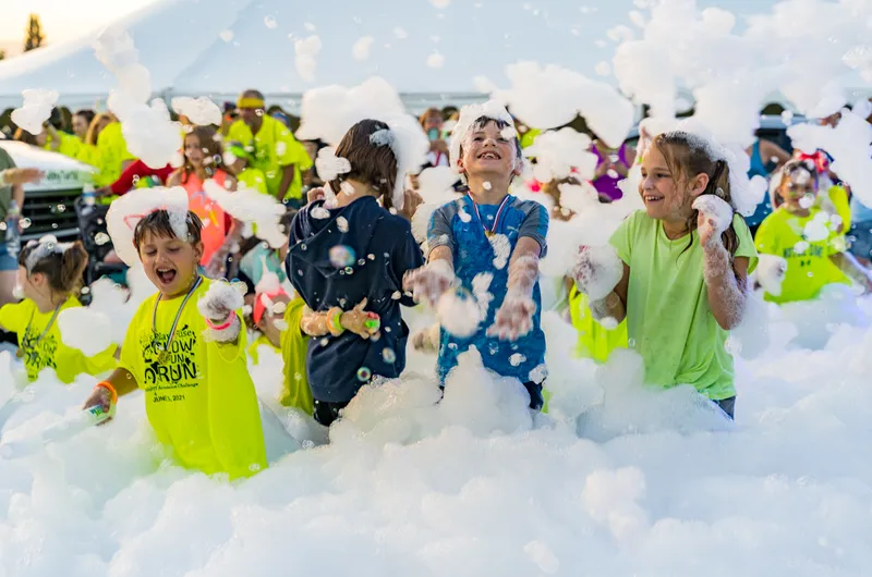 Group of kids cheering at a foam party setup in a backyard